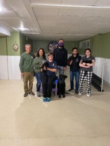 A group of seven people posing in a basement room with casual attire.