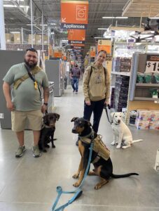 Two men with four dogs in a hardware store aisle.